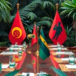 A diplomatic meeting table with flags of Senegal and Burkina Faso, surrounded by plants, symbolizing cooperation.