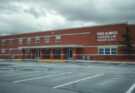 Quiet school exterior during election day, with empty parking lot and cloudy sky, reflecting slow turnout in Virginia.